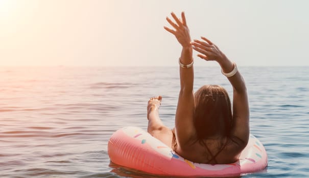 Woman summer sea. Happy woman swimming with inflatable donut on the beach in summer sunny day, surrounded by volcanic mountains. Summer vacation concept