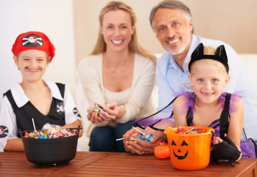 Happy family, portrait and halloween party in home, trick or treat and happiness in childhood. Man, woman and kids for holiday with candy, pumpkin and fairy costumes for love and celebration in house.