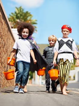 Halloween, children or trick and treat portrait outdoor in neighborhood for fun and dress up. A group of young kids together for happiness, celebrate holiday and diversity with candy or sweets.