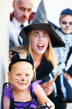 Portrait, halloween and a family in costume for fantasy tradition or holiday celebration. Mother, father and children at a door in trick or treat clothes for dress up on allhallows eve together.