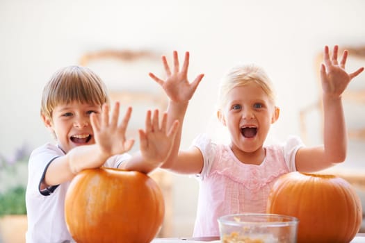 Halloween, hands and carving a pumpkin with children at a home table for fun and bonding. Boy and girl or young kids as siblings together for creativity, holiday lantern and portrait or play in house.