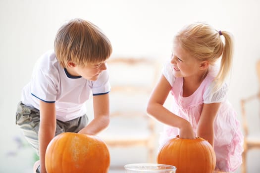 Halloween, happy and carving a pumpkin with children at a home table for fun and bonding. Boy and girl or young kids as siblings together for creativity, holiday lantern and craft and play in a house.