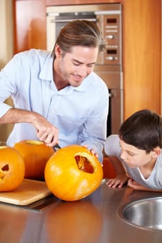 Halloween, pumpkin and father with kid in a kitchen for carving, learning or festival preparation at home. Family, love and parent with fruit, knife and creative lesson while. bonding with boy child.