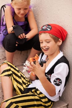 Siblings, playing and halloween costume by outdoor stairs, toys and happiness in childhood. Boy, girl and smile face for holiday with finger puppet games, theme clothes fairy and pirate in backyard.