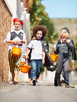 Halloween, children or trick and treat portrait outdoor in neighborhood for fun and dress up. A group of young kids together for happiness, celebrate holiday and diversity with candy or sweets.