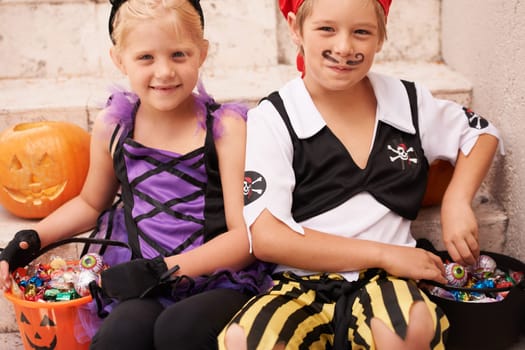 Siblings, portrait and halloween costume on stairs, candy and happiness in childhood. Boy, girl or smile face for holiday party event with trick or treat, theme clothes fairy or pirate by backyard.