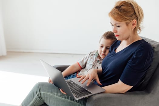 Mom with son sitting in chair with laptop