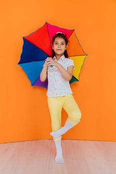 Little girl with multicolored zant from rain on orvange background