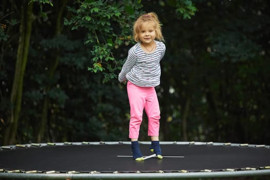 Child jumping on a trampoline in the evening garden in Denmark.