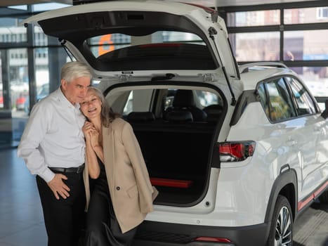 Mature Caucasian couple choosing a car looks at the trunk