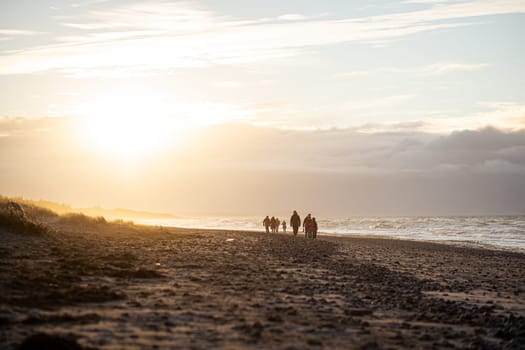 Tisvildeleje, Denmark - January 21, 2022: People walking at Tisvildeleje beach during sunset