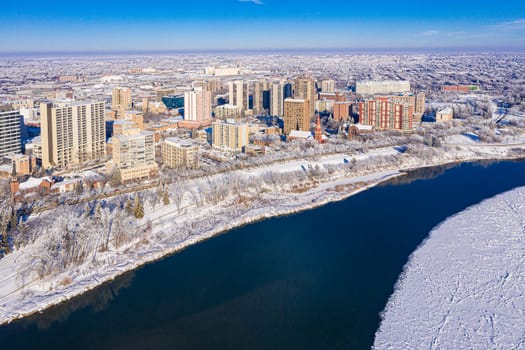 Behold the winter wonderland of Downtown Saskatoon from the sky. This drone image captures the snowy cityscape, frozen river views, and the serene beauty of urban life in the chill of winter.