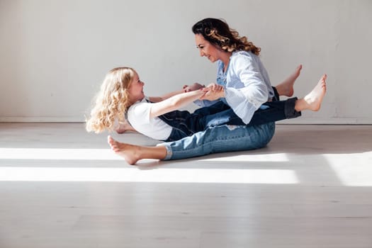 Mom and daughter in jeans sit together cuddling kisses