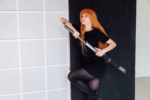 cosplayer anime with red hair holds a Japanese sword