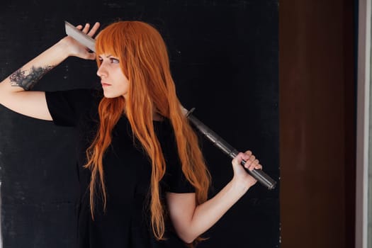 cosplayer anime with red hair holds a Japanese sword