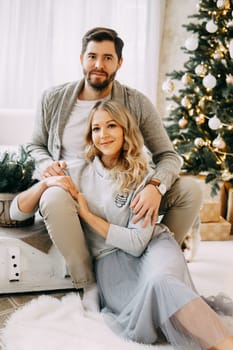 Happy family: mom, dad and pet. Family in a bright New Year's interior with a Christmas tree.