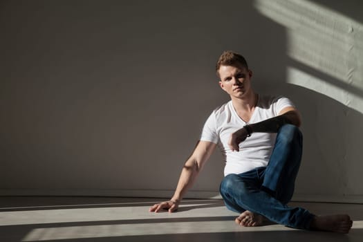 man in jeans sits on the floor in the room