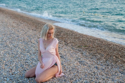 Portrait of a fashionable blonde woman on the beach by the sea