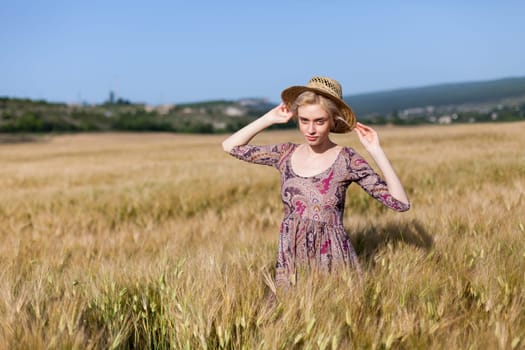 a smoldering fashionable woman in a dress in a field of ripe wheat