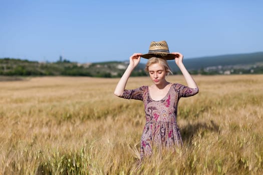 a smoldering fashionable woman in a dress in a field of ripe wheat