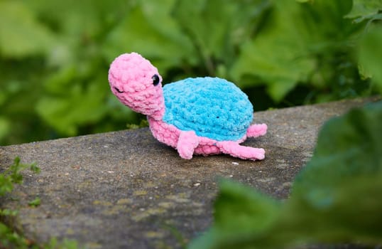 Cute knitted toy turtle in the garden.