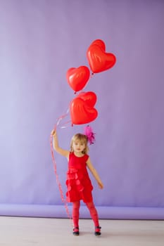 girl holds red balloons in the shape of a heart