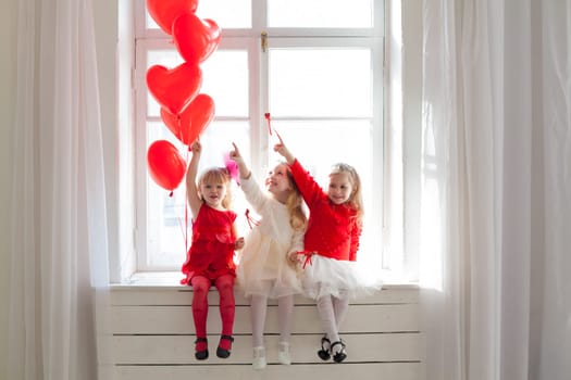 Three girl girlfriends sit by the window with holiday balloons