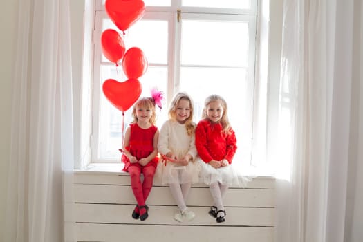 Three girl girlfriends sit by the window with holiday balloons