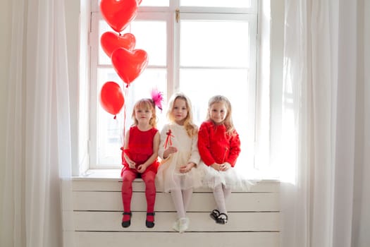 Three girl girlfriends sit by the window with holiday balloons