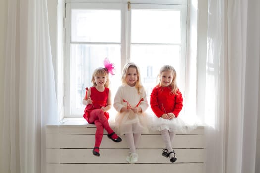 girl girlfriends sit by the window in white and red dresses