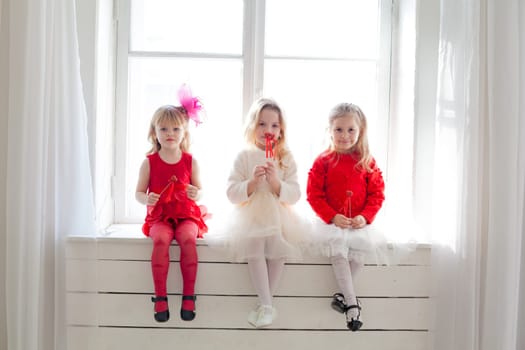 girl girlfriends sit by the window in white and red dresses
