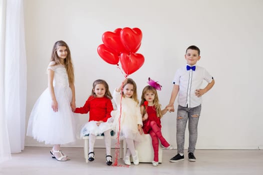 four girls and a boy in a white room with red balloons for the holiday