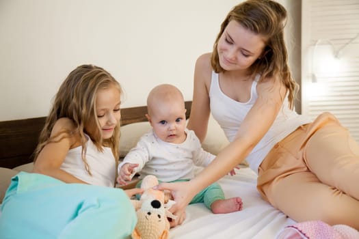 three girls sisters play in the bedroom on the bed in the morning