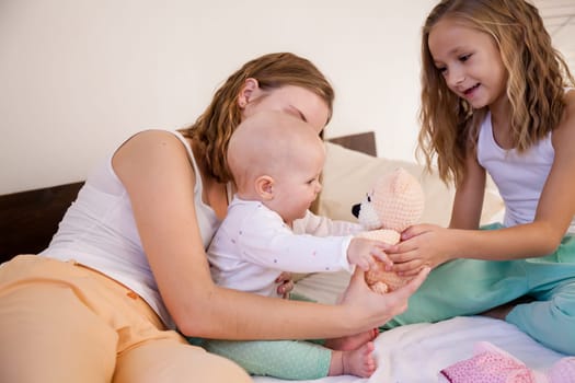 three girls sisters play in the bedroom on the bed in the morning