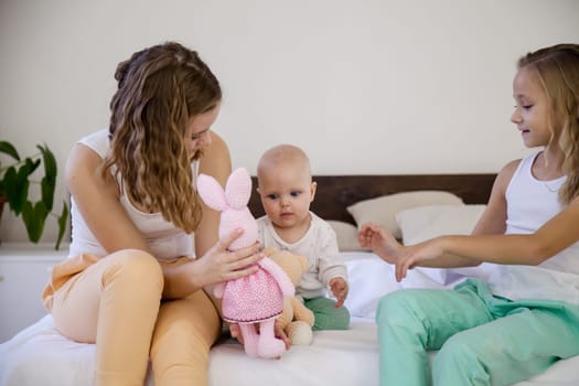 three girls sisters play in the bedroom on the bed in the morning