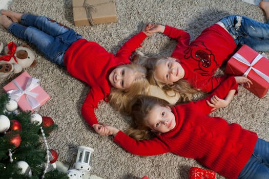 Three little girl girlfriends open Christmas presents to the new year