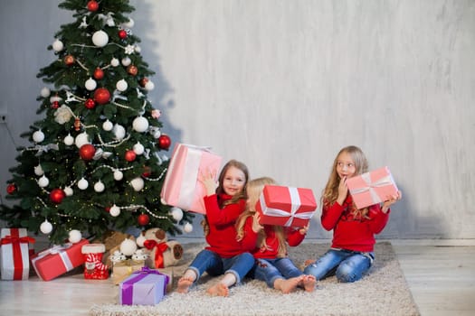 Three little girl girlfriends open Christmas presents to the new year