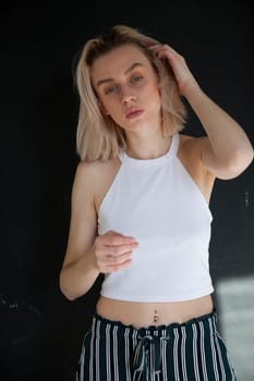 portrait of a beautiful blonde woman in striped pants against a dark background