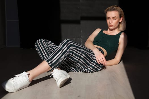 portrait of a beautiful blonde woman in striped pants against a dark background