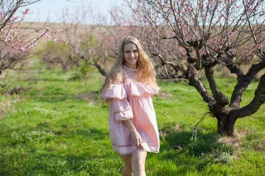 Woman blonde in dress walks in the flowering garden