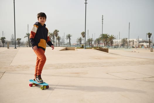 Full length portrait of a multi ethnic handsome confident teenage boy skateboarding on an outdoor urban skatepark. People. Lifestyle. Extreme sport concept. Leisure activity