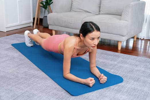 Fit young asian woman planing on the living room floor. Healthy lifestyle workout training routine at home. Balance and endurance exercising concept. Vigorous