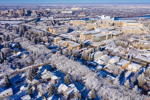 Behold the winter wonderland of Downtown Saskatoon from the sky. This drone image captures the snowy cityscape, frozen river views, and the serene beauty of urban life in the chill of winter.