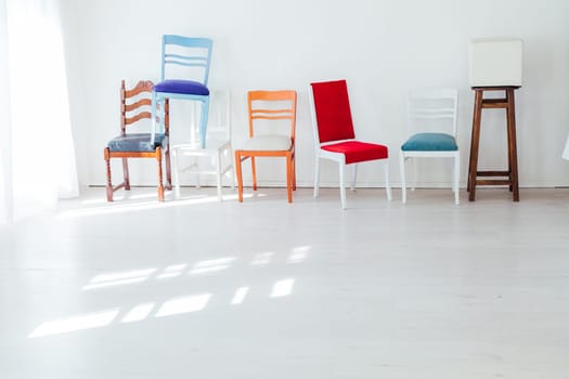 many different chairs stand on top of each other in the interior of an empty white room