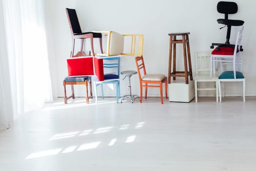 many different chairs stand on top of each other in the interior of an empty white room