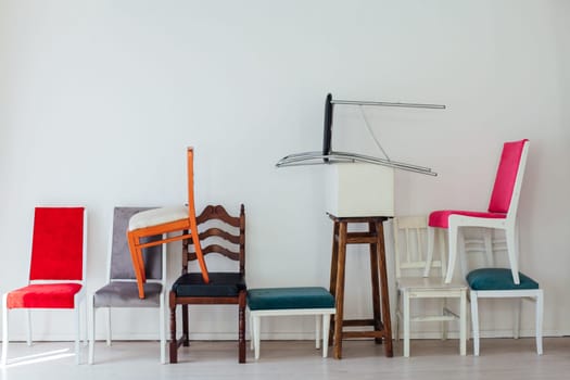 many different chairs stand on top of each other in the interior of an empty white room