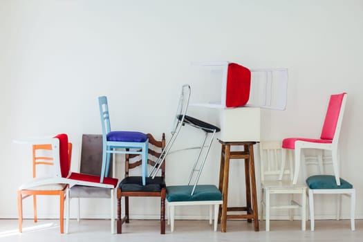 many different chairs stand on top of each other in the interior of an empty white room