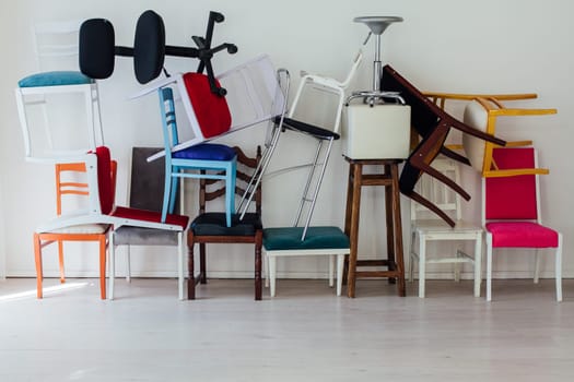 many different chairs in disarray in the interior of an empty white room