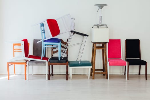 many different chairs in disarray in the interior of an empty white room