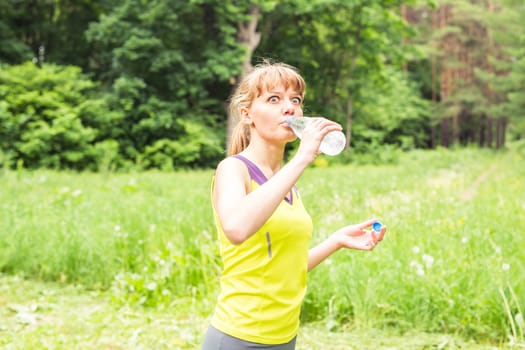 Portrait of amazed young fitness woman drinking at water bottle.